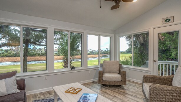 A sunroom with large windows, a ceiling fan, wicker furniture, and a view of a golf course. - 2 BR + Loft/2BA Tarpon Pond Cottage! Great Views! Amenity access included (Seabrook Island)