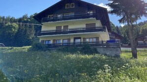Ein mehrstöckiges Gebäude mit Balkonen, umgeben von einer grünen Wiese und Bäumen.