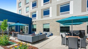 An outdoor patio with seating, a barbecue area, and a flower garden.