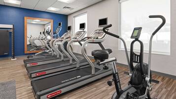 A gym with multiple treadmills, a stationary bike, and a mirror.
