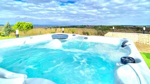 Un bain à remous avec un mur en pierre et une vue sur le paysage.