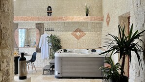 Un espace de bien-être avec un mur en pierre, un jacuzzi et des plantes en pot.