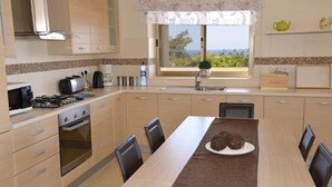 Een moderne keuken met een eethoek, met een fornuis, magnetron en uitzicht op de omgeving.