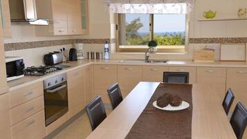 A modern kitchen with a dining area, featuring a stove, microwave, and a view of the outdoors.