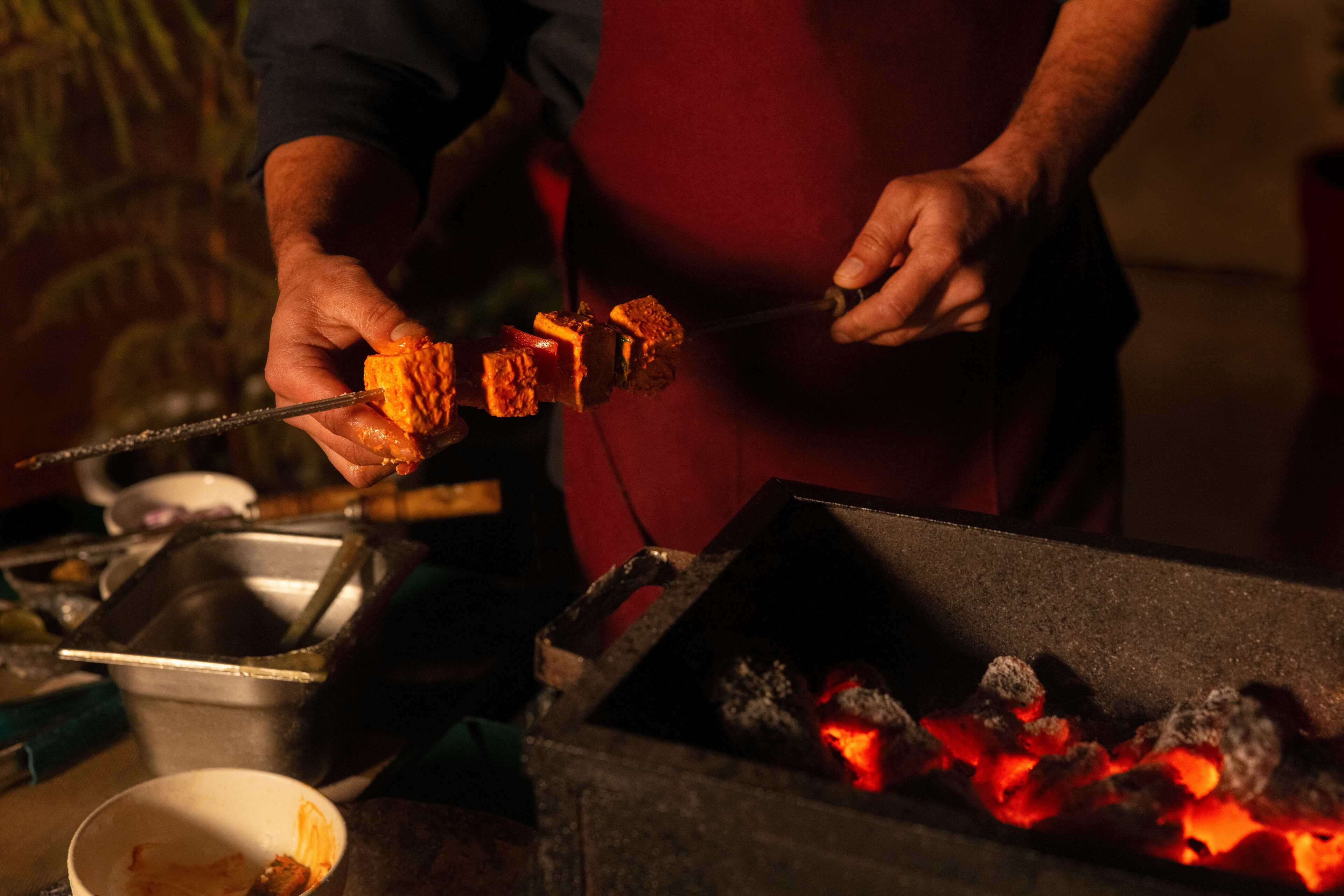A person grilling meat over an open flame.