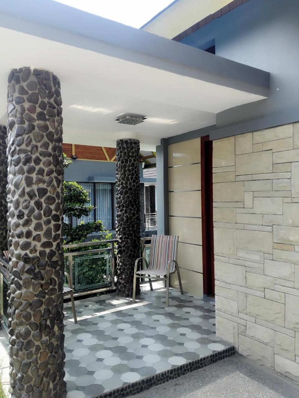 A modern outdoor area with a stone pillar, a chair, and a patterned floor.