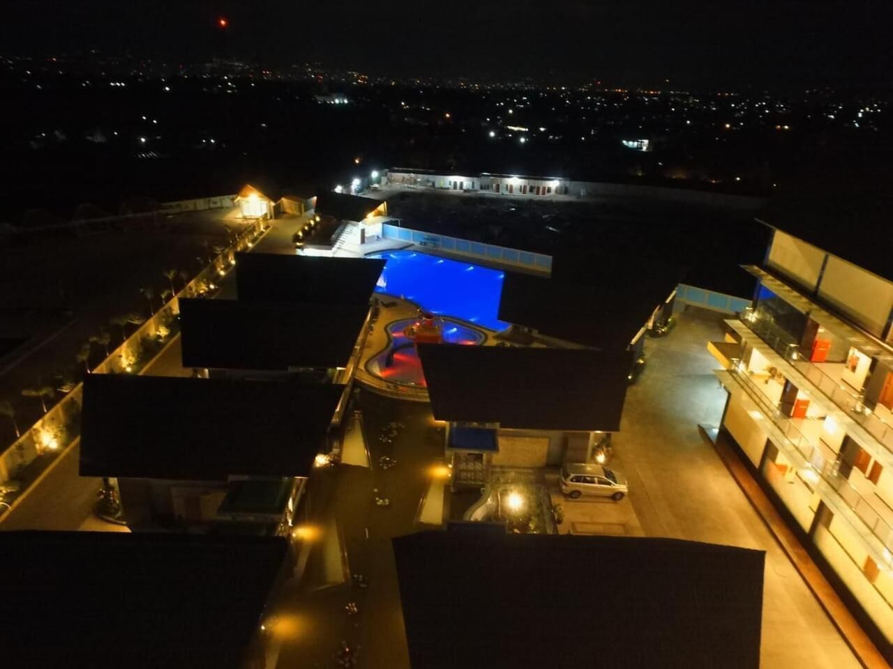 Un hotel con piscina, varias plantas y zona de estacionamiento.
