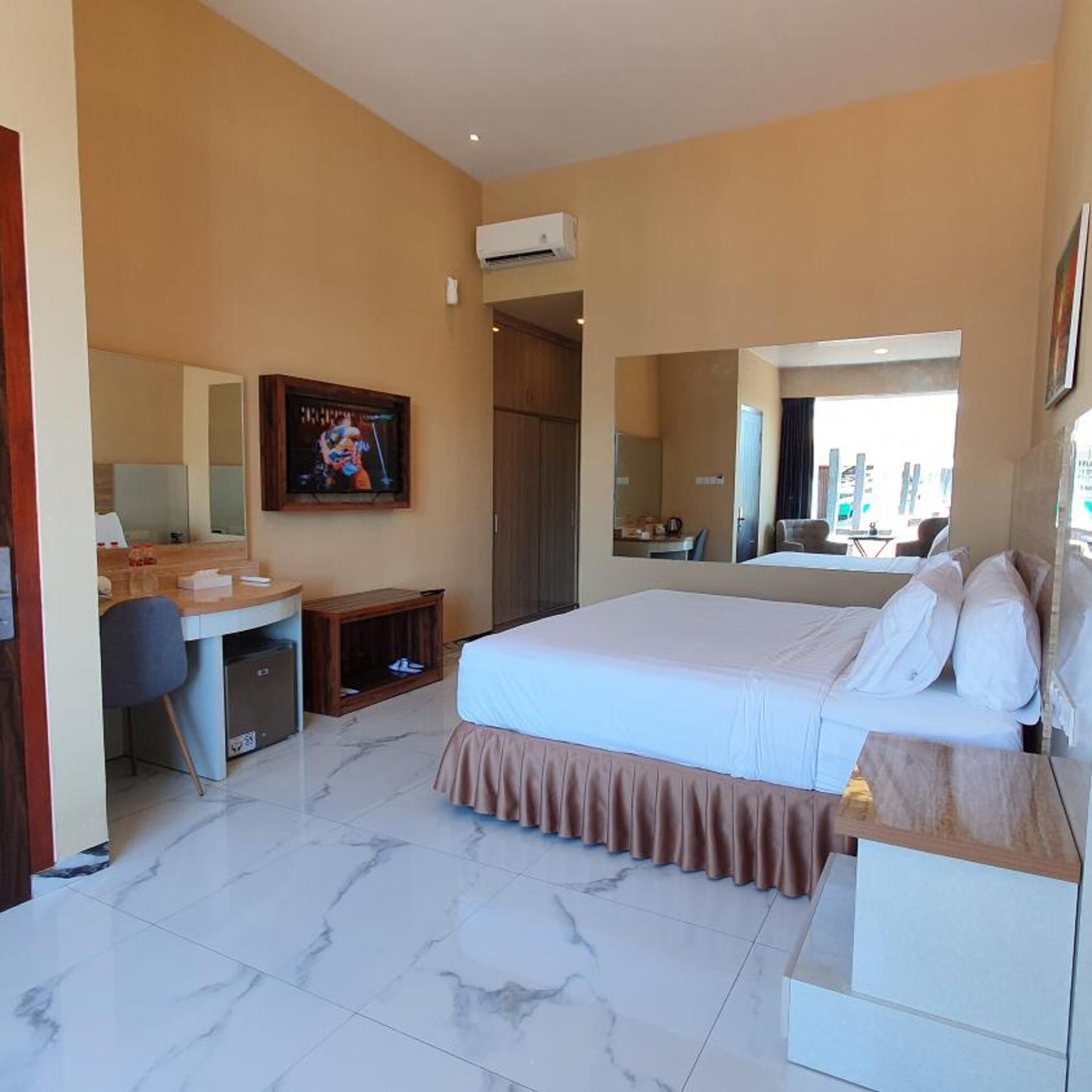 Une chambre d’hôtel avec un lit, un bureau, une chaise et un grand miroir.