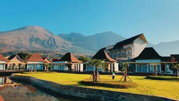 A resort with multiple buildings, a swimming pool, and a mountain in the background.