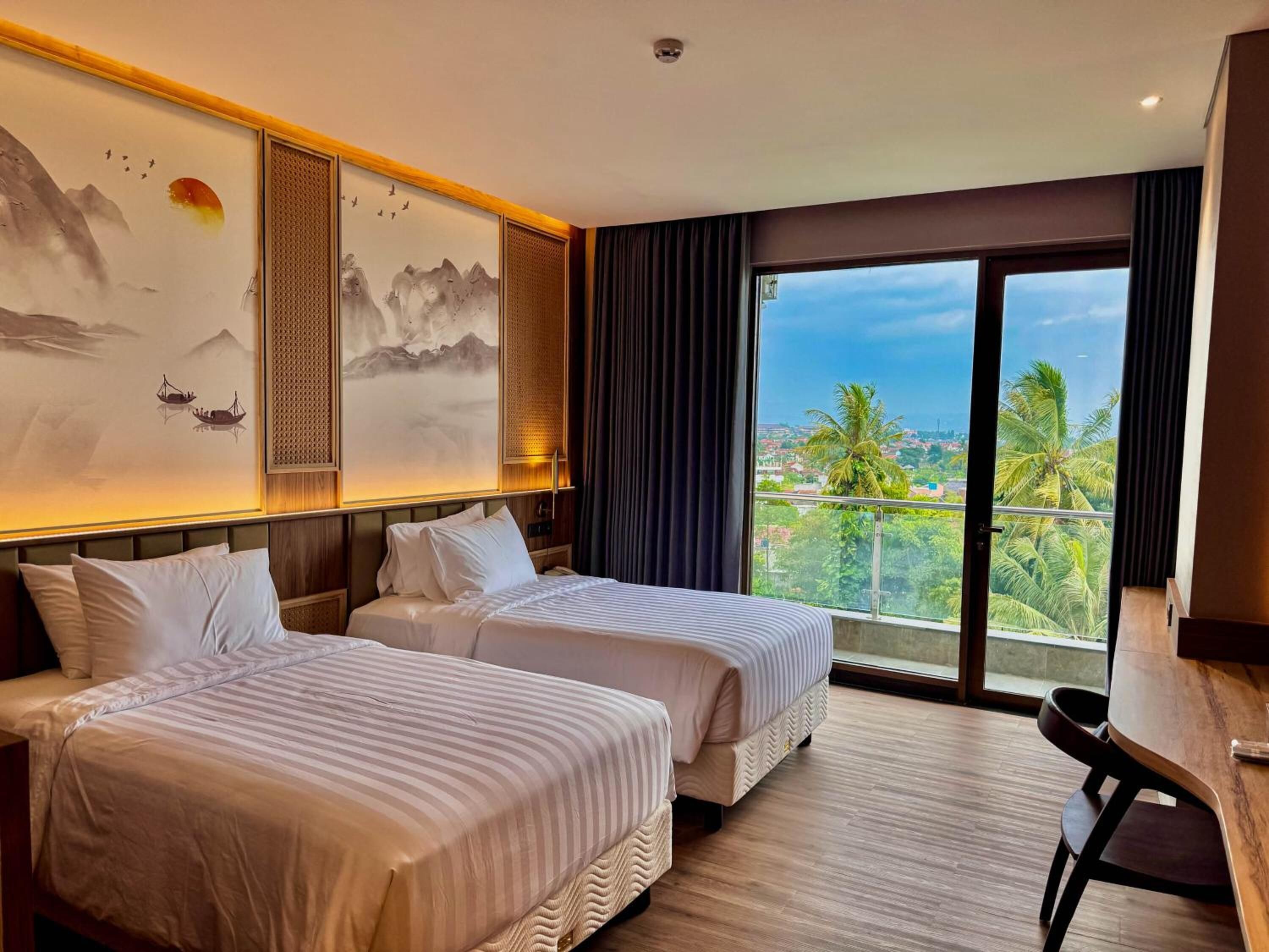 A hotel room with two beds, a large window with a view, and artwork on the wall.
