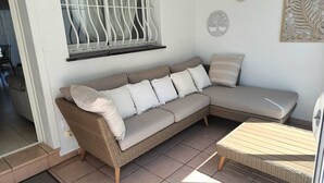 A wicker sectional sofa with multiple cushions, a small table, and a window with white bars. - Superb summer house with swimming pool, parking, wifi and air conditioning  (L'Escala)