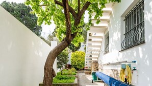 A narrow courtyard with a tree, a blue hose reel, and a staircase leading to an upper level. - Superb summer house with swimming pool, parking, wifi and air conditioning  (L'Escala)
