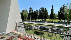 Ein Balkon mit Tisch und Stühlen, mit Blick auf einen Parkplatz mit Autos und Bäumen.