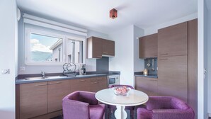 A modern kitchen with wooden cabinets, a built-in oven, and a window overlooking a scenic view. - Tempologis Le Saint Germain Grenoble (Grenoble)