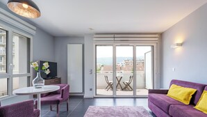 A modern living room with a purple sofa, a small round table, and a TV. - Tempologis Le Saint Germain Grenoble (Grenoble)