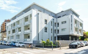 A multi-story hotel with balconies, a parking lot, and a gated entrance. - Tempologis Le Saint Germain Grenoble (Grenoble)