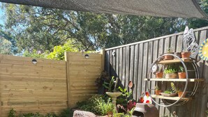A patio with a glass table, wicker chairs, a brick wall, and a wooden fence. - Highlands Escape  Moss Vale (Moss Vale)
