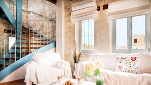 A living room with a staircase, a white sofa, a coffee table with pastries, and a vase with flowers. - Beachfront villa w/private pool, ping pong and BBQ (Chania)