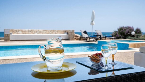 A clear view of a swimming pool with lounge chairs and a table with a pitcher and glasses. - Beachfront villa w/private pool, ping pong and BBQ (Chania)