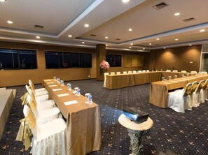 A conference room with long tables, chairs, and a projector on a stand.