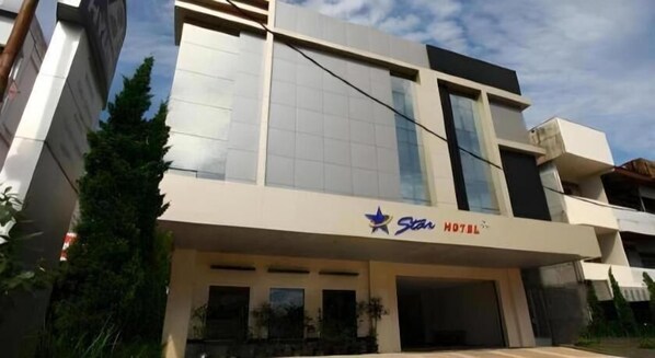 A modern hotel with a flat roof, large windows, and a sign indicating it is a Star Hotel.