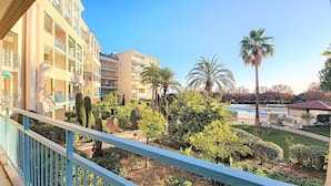 Un patio de hotel con piscina, palmeras y un jardín bien cuidado.
