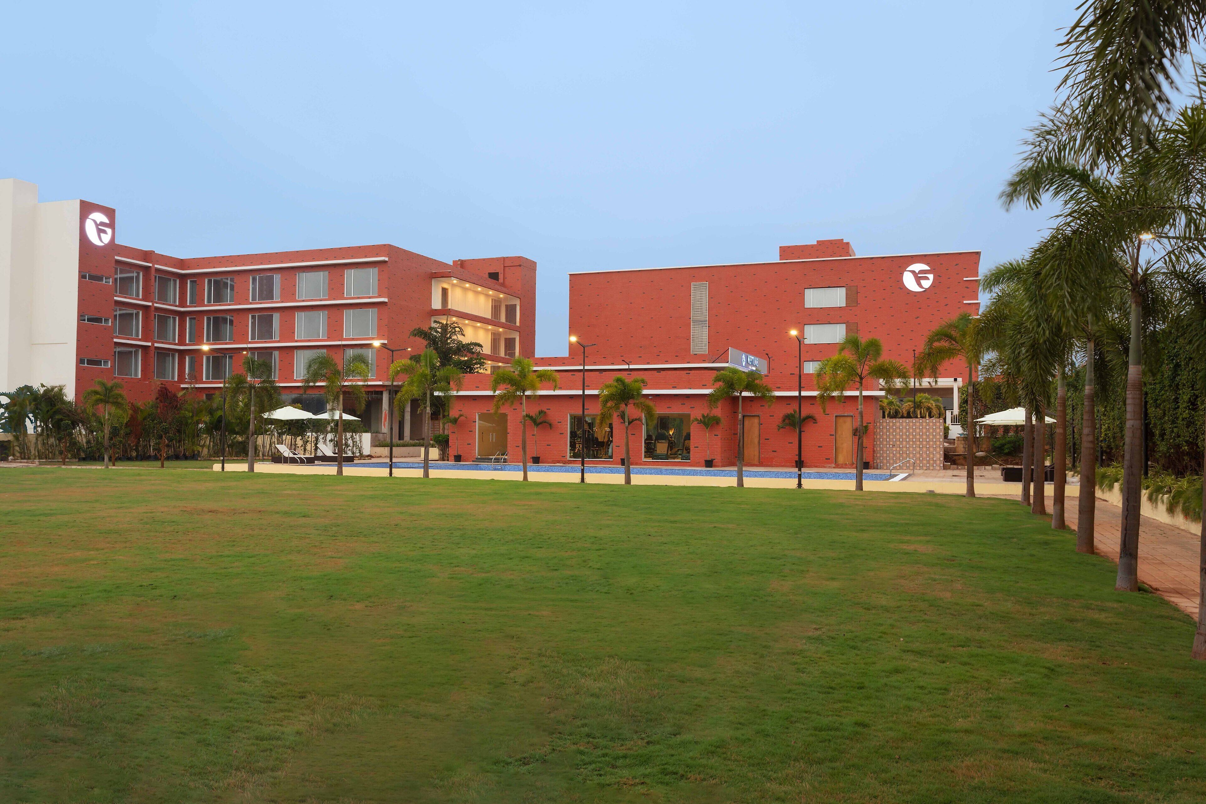 Um hotel com fachada de tijolos vermelhos, várias varandas e uma piscina.