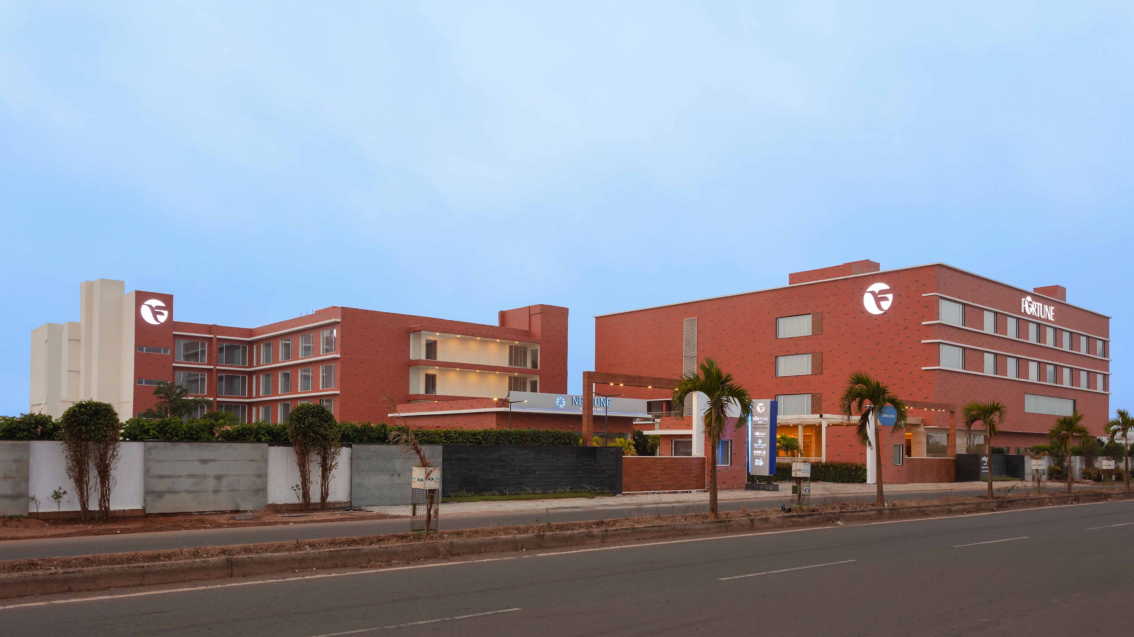 A modern hotel with a red facade, multiple floors, and a prominent 'Fortune' sign.