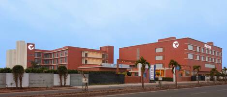 A modern hotel with a red facade, multiple floors, and a prominent 'Fortune' sign.