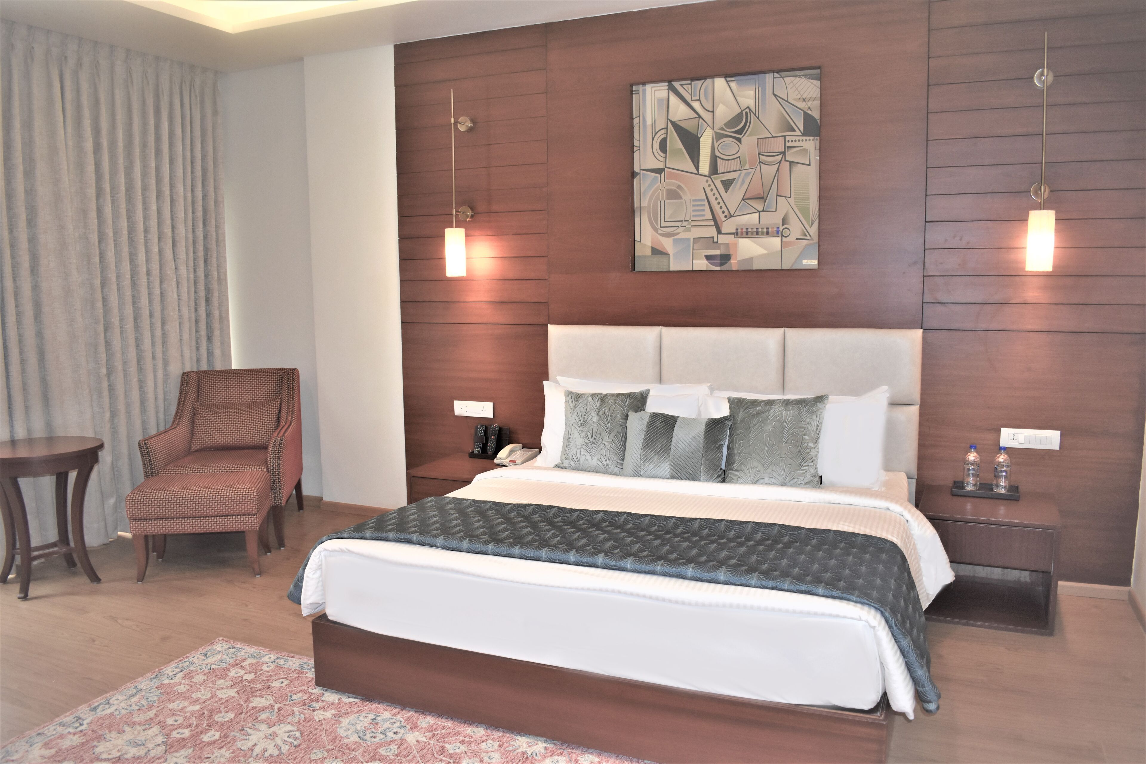 Une chambre d’hôtel moderne, dotée d’un grand lit, d’une chaise, d’une table de chevet et d’une œuvre d’art accrochée au mur.