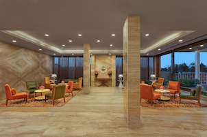 A spacious lobby with modern furniture, a central decorative wall, and large windows.
