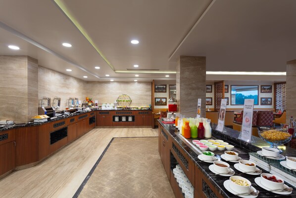 Un buffet con diversas opciones de comida y bebidas, un área central de servicio y un espacio de asiento con vistas.