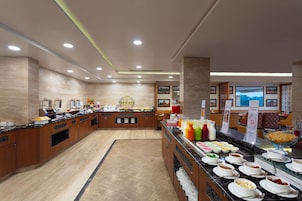 A buffet setup with various food items and beverages, a central serving area, and a seating area with a view.