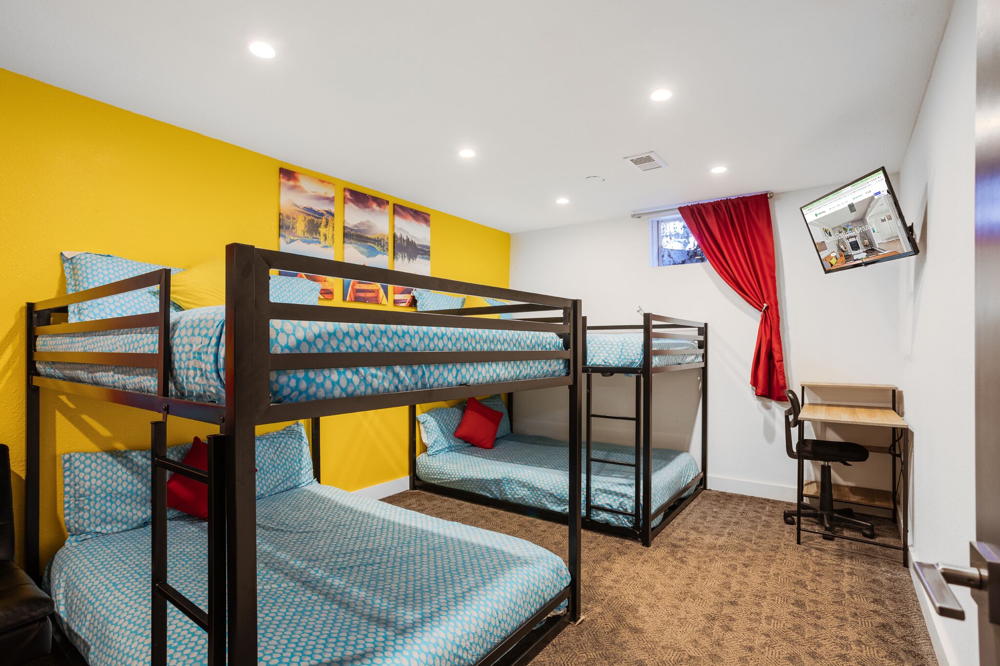 A dormitory room with bunk beds, a desk, and a computer monitor.