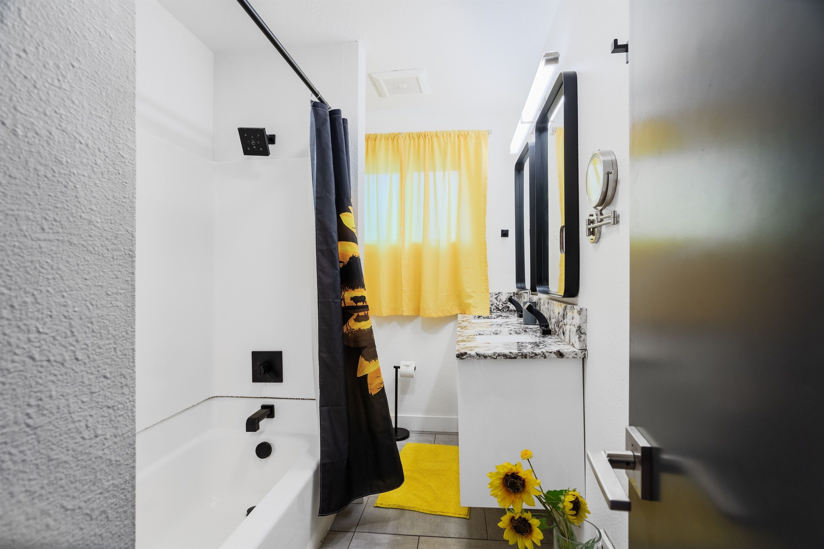 A bathroom with a bathtub, a sink, a mirror, and a yellow towel.