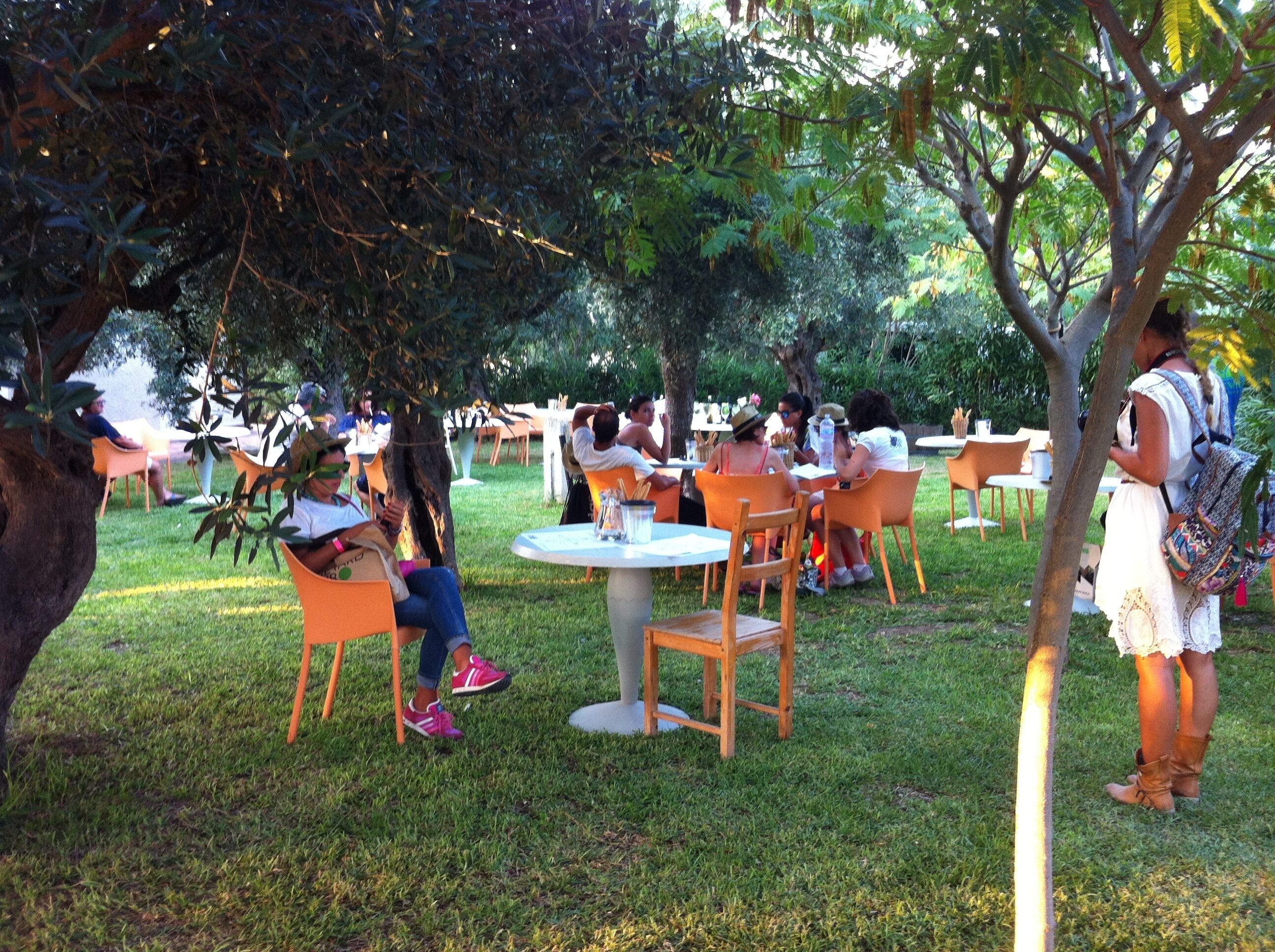 An outdoor seating area with tables and chairs under trees.