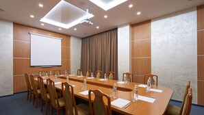 A conference room with a long table, chairs, a projector screen, and a ceiling light. - Hotel Druzhba (Kyiv)