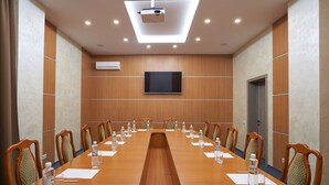 A conference room with a long table, chairs, a projector, and a TV on the wall. - Hotel Druzhba (Kyiv)