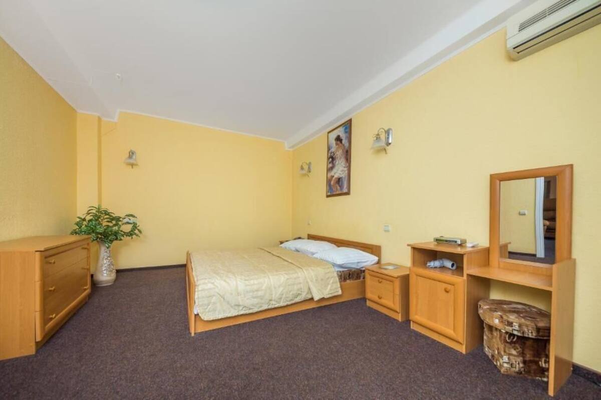 Ein Schlafzimmer mit einem Bett, Nachttischen, einem Schminktisch und einem Blumentopf.