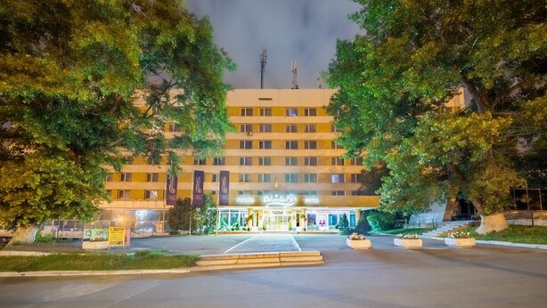 A hotel with a central entrance, multiple floors, and a flag on the roof. - Hotel Druzhba (Kyiv)