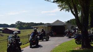 Un grupo de motocicletas estacionadas en un camino pavimentado, con un edificio al fondo.