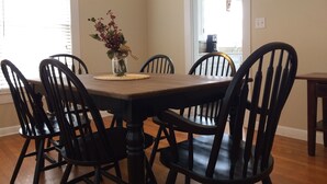 Una mesa de comedor con seis sillas, un florero con flores e iluminación colgante.