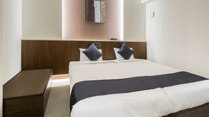 Habitación de hotel con una cama grande, cabecera de madera, una mesita de noche pequeña y un espejo adosado a la pared.