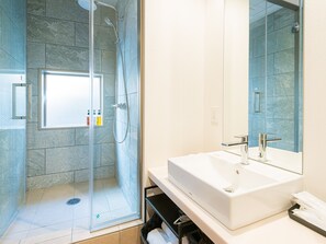 A modern bathroom with a glass-enclosed shower, a large mirror, and a white sink.