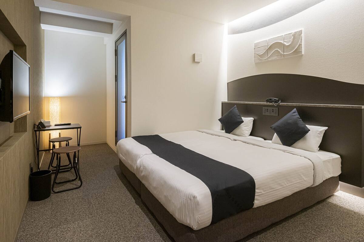 Une chambre d’hôtel avec un lit, un bureau et une chaise.