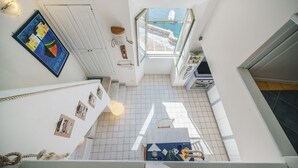 Un couloir étroit donnant sur un balcon et une salle à manger.