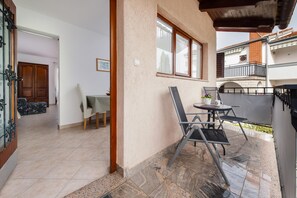 A patio area with a table and chairs, a wooden door, and a view of the street. - Apartments and Room Silvana (Rovinj)