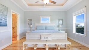 Une chambre à coucher avec un lit, un banc, un ventilateur de plafond et une fenêtre.