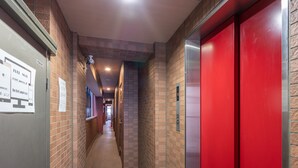 En gang med rød elevator, brandalarm og skilt der angiver Wi-Fi.