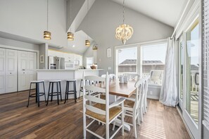 Uma cozinha moderna com armários brancos, uma mesa de jantar de madeira e banquetas.